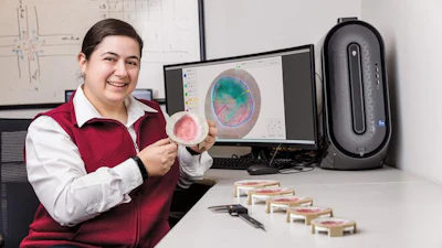 Scientist holding petri dish with bacterial culture at laboratory workstation with analysis software displayed on monitors