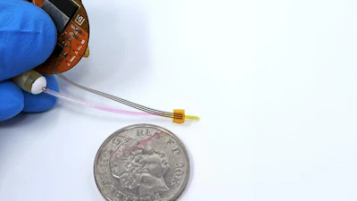 Miniature circuit board component held next to UK coin for scale comparison