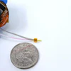 Miniature circuit board component held next to UK coin for scale comparison