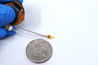 Miniature circuit board component held next to UK coin for scale comparison