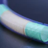 Blue flexible tube with cyan translucent sections showing internal mesh structure against dark background