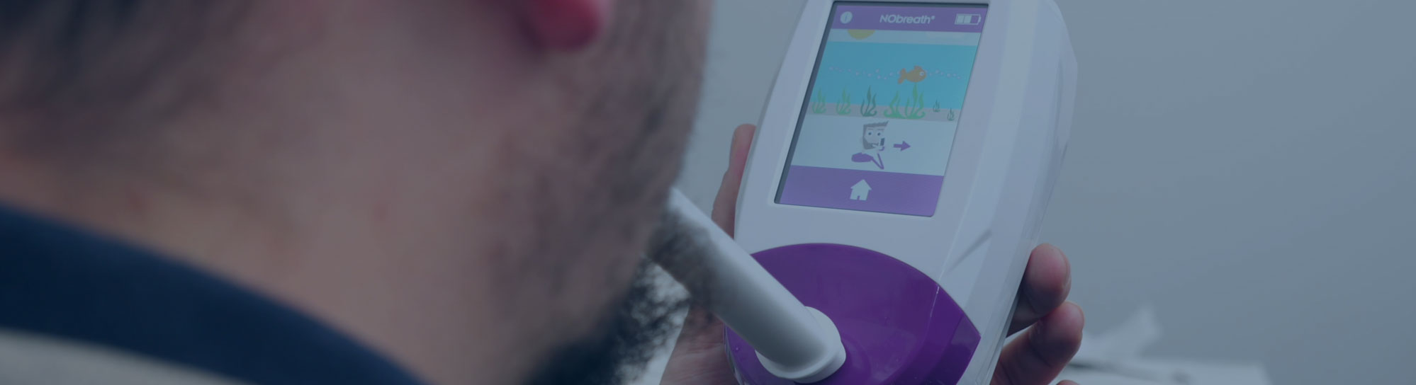 Person holding white handheld medical diagnostic device with purple accents and touchscreen display