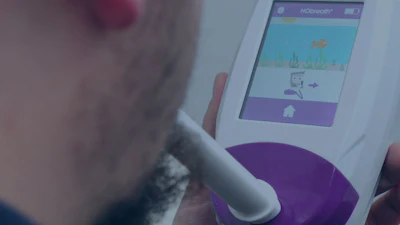 Person holding white handheld medical diagnostic device with purple accents and touchscreen display