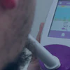 Person holding white handheld medical diagnostic device with purple accents and touchscreen display