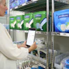 Warehouse worker scanning inventory on mobile device in front of shelving with incontinence care product packages